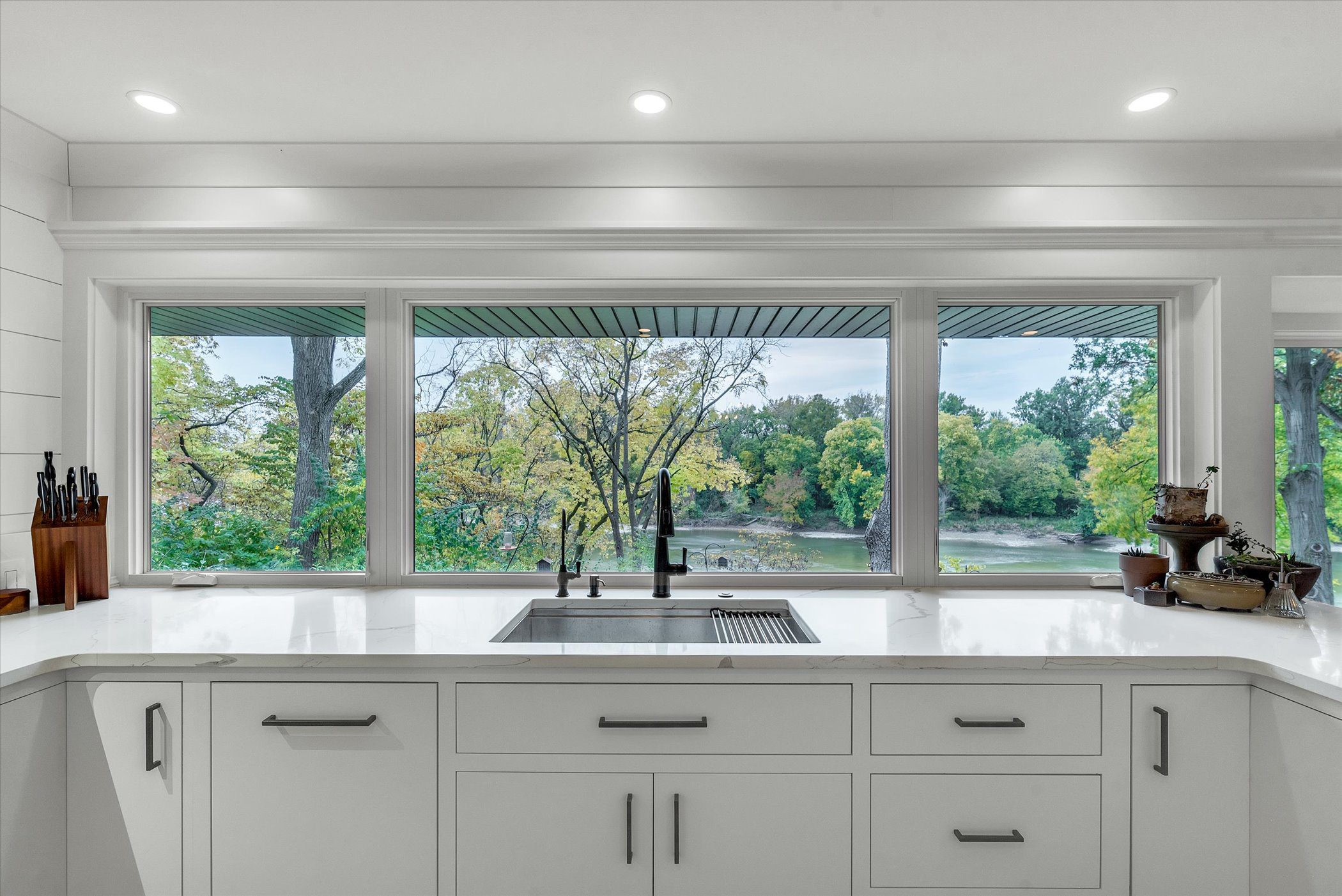 Signature Renovating kitchen with a large window showcasing a peaceful river and lush trees.